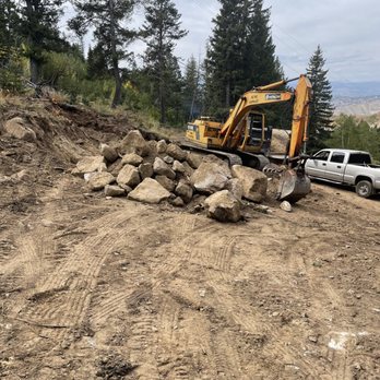 ACME Asphalt excavator moving large rocks during site preparation
