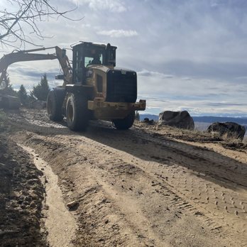 ACME Asphalt equipment grading a dirt road before paving